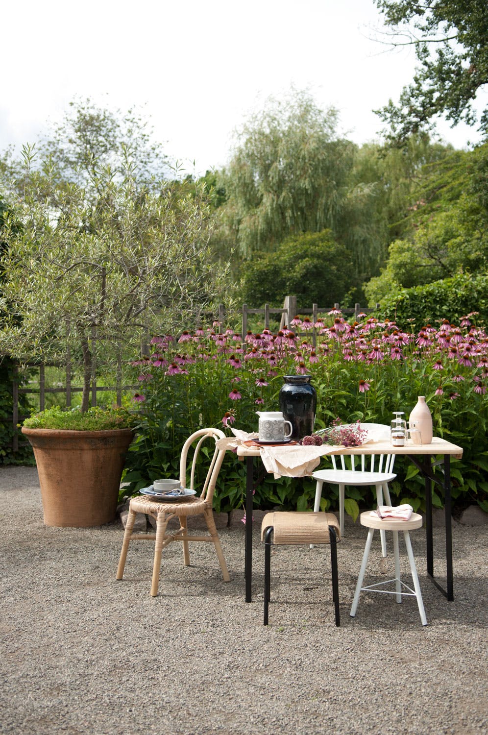 Kul krakk av naturmaterialer Sommerlig utebord foran et blomsterhav i hagen